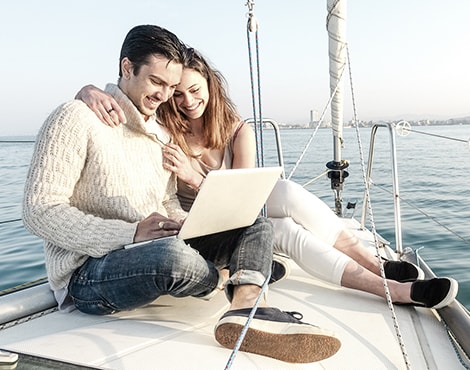 Young couple looking at laptop on sailboat
