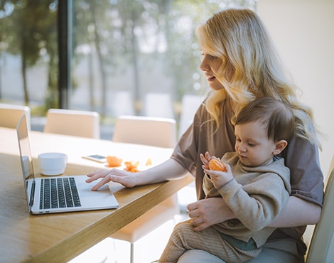 Mother and child using laptop in kitchen.