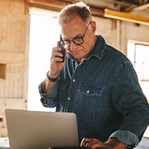 Man talking on phone while using laptop