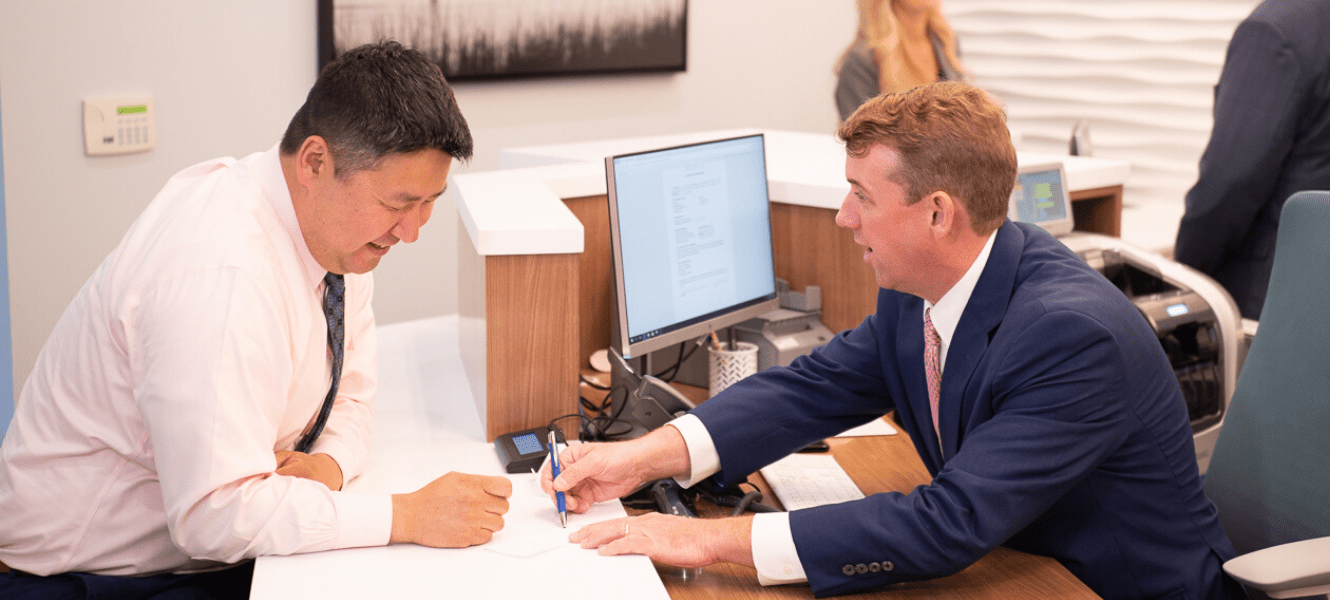 two men looking at paper at desk