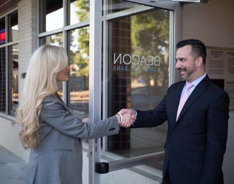 man and woman shaking hands at doorway